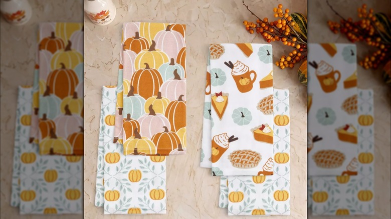 Un ensemble de torchons de cuisine à imprimé d'automne de Target avec un motif de citrouille et un motif de latte d'automne.