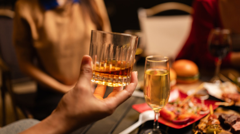 Une personne tenant un verre de whisky dans un bar.