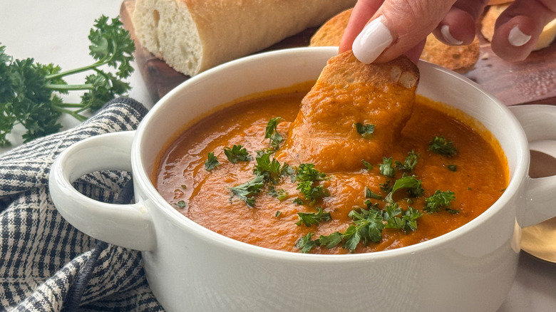 main trempant le pain dans la soupe