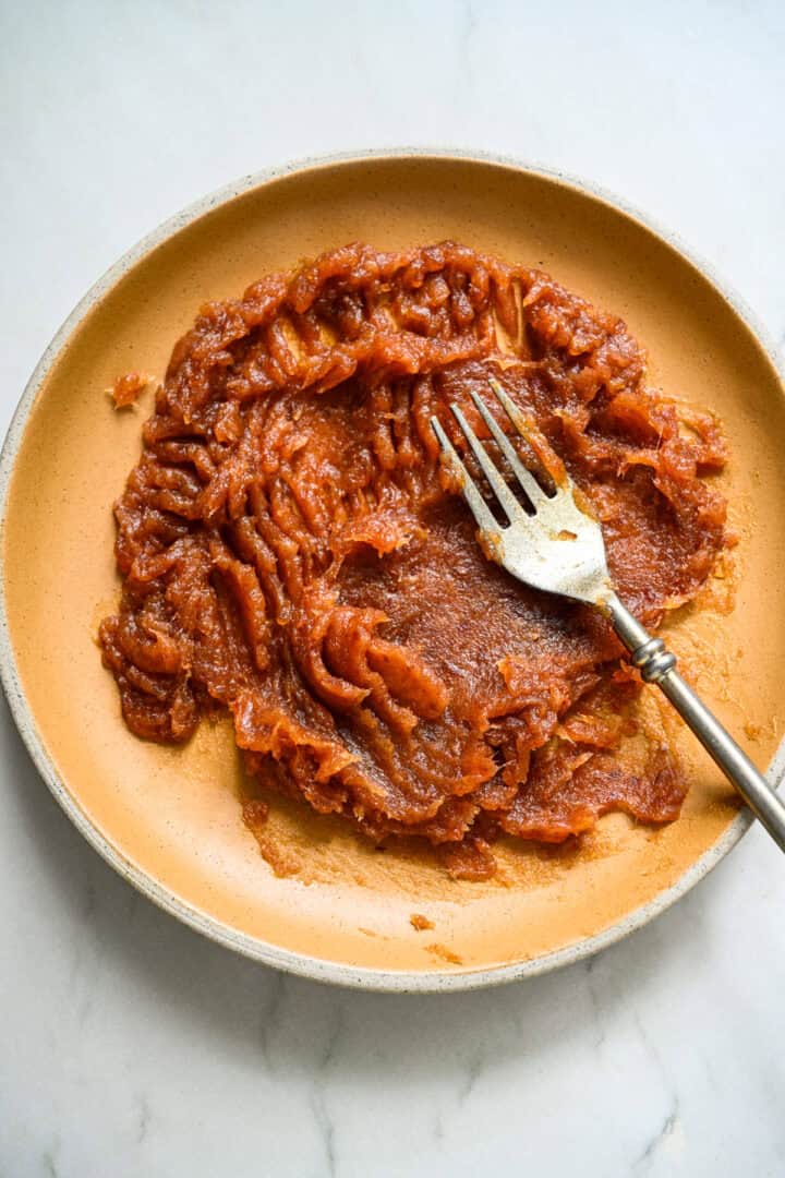 Purée de dattes sur une assiette jaune avec une fourchette.
