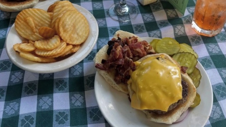 Un repas chez JG Melon à New York avec un cheeseburger et des cornichons dans une assiette et des frites dans une autre