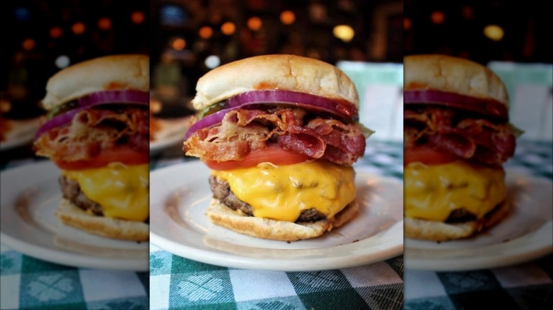 Un délicieux cheeseburger sur une surface sombre avec diverses garnitures et condiments