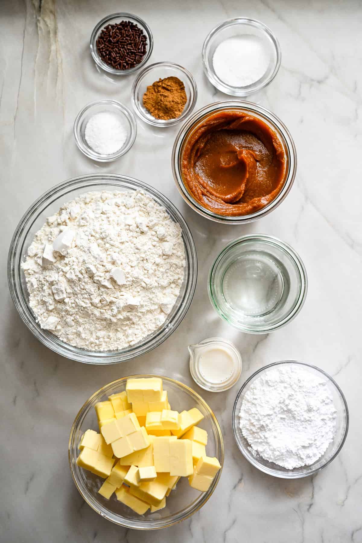 Vue aérienne des ingrédients pour les tartelettes à la citrouille dans des bols séparés.