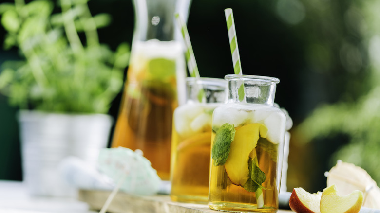 Carafe à thé glacé et verre avec tranches de pêches fraîches.