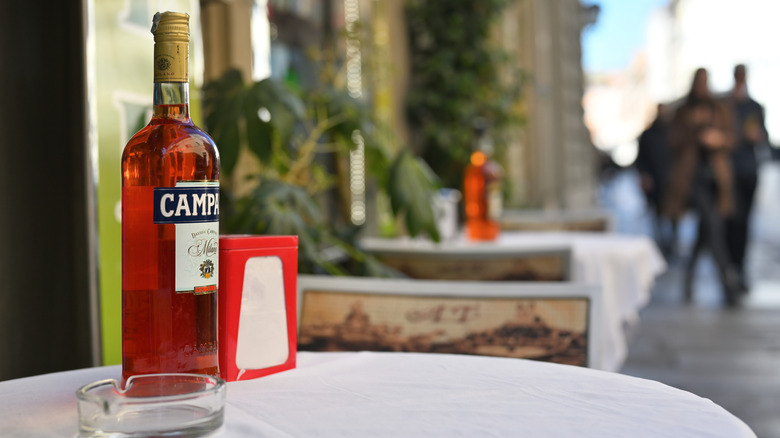 Une bouteille de Campari sur une table de café-terrasse.