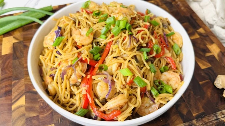 crevettes lo mein dans un bol blanc avec nouilles, protéines, salade de chou et ciboulette visibles