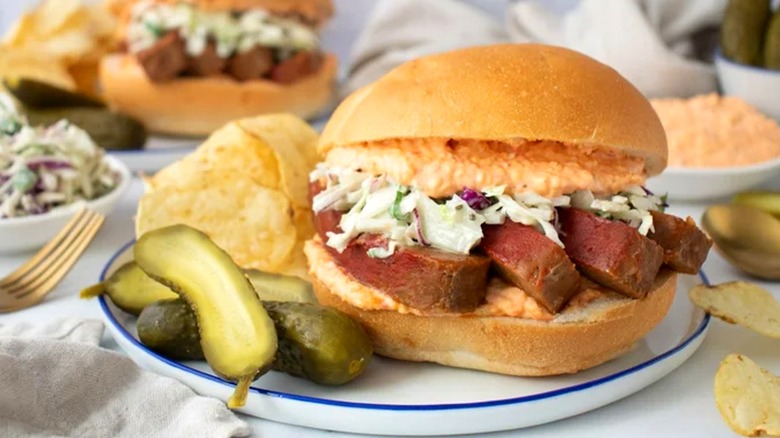 un sandwich rempli de pain de viande, de fromage au piment et de salade de chou sur une assiette