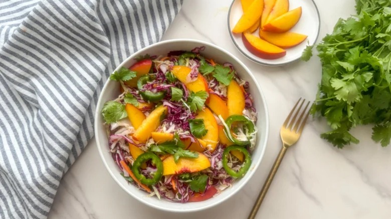 Salade de chou aux pêches épicée dans un bol blanc sur une table en marbre
