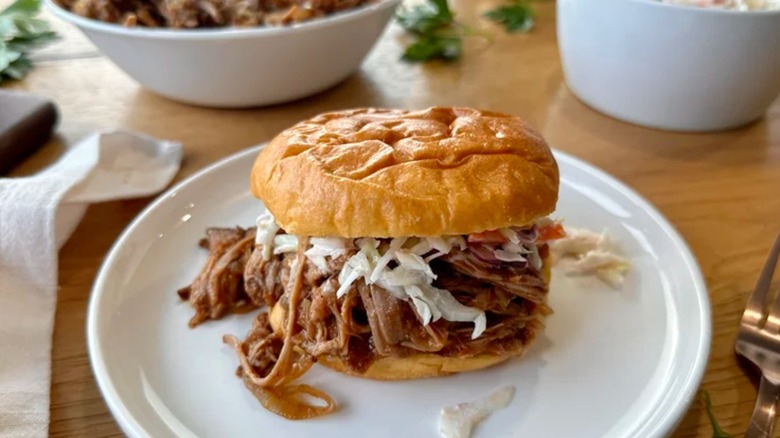 un sandwich au porc effiloché avec salade de chou sur une assiette blanche