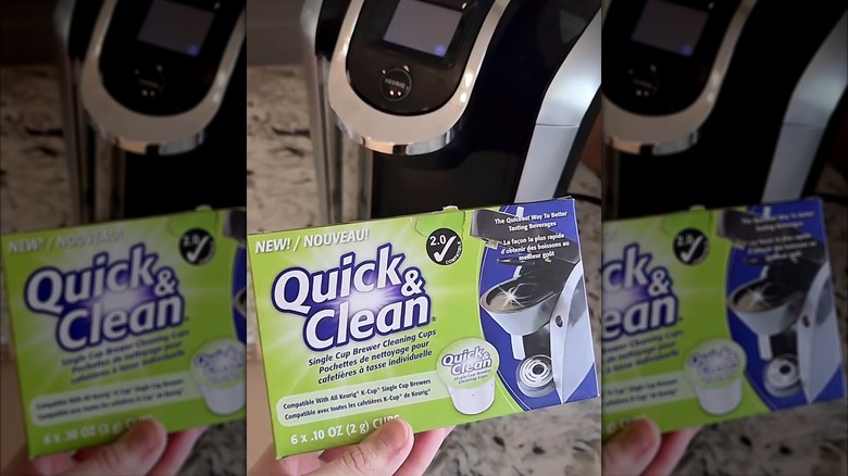 une main tenant un paquet de dosettes Quick & Clean