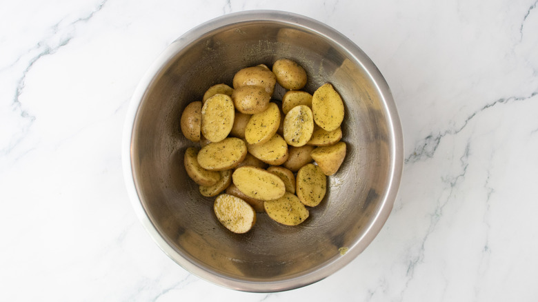 Pommes de terre crues dans un grand bol assaisonnées d'herbes et d'épices
