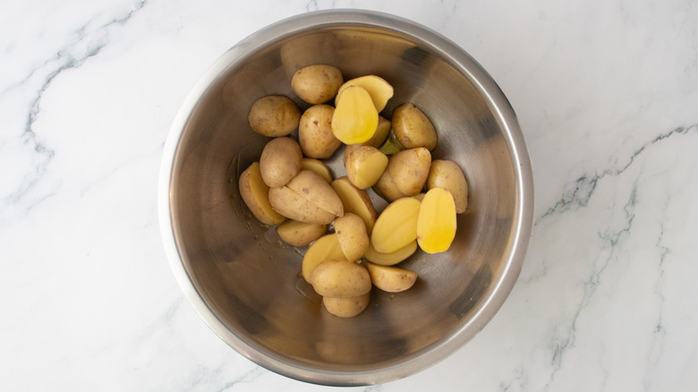 Couper des pommes de terre grelots dans un grand bol, arroser d'huile d'olive