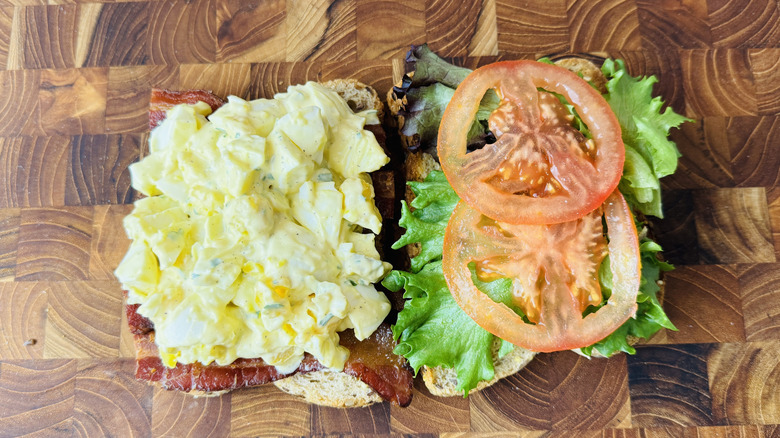 Club sandwich à la salade aux œufs ouvert sur planche de bois