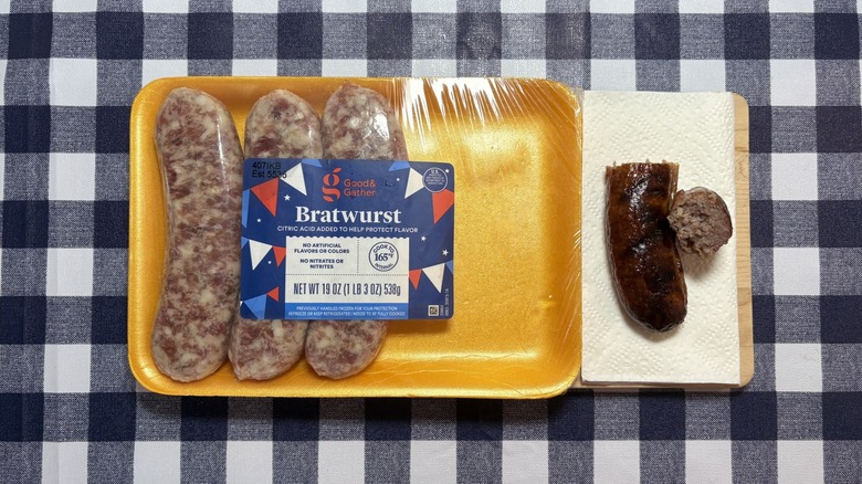Ciblez le paquet Good & Gather Brat à côté de saucisses cuites sur une nappe à carreaux