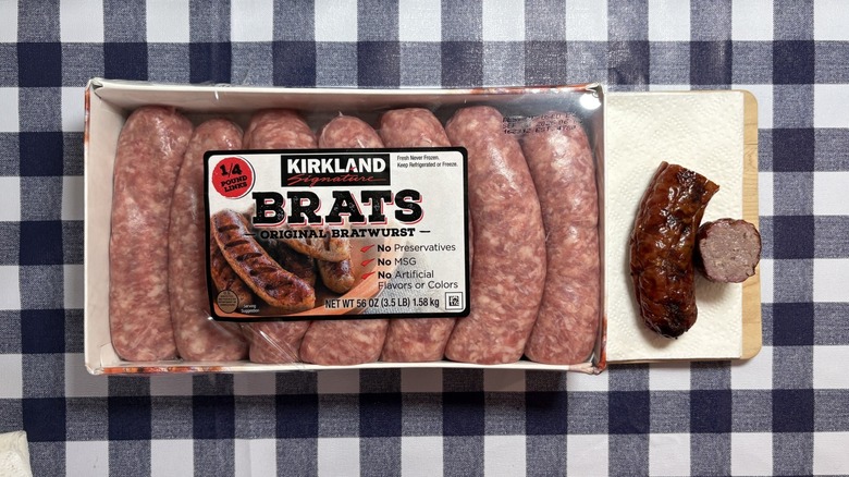 Paquet de brat de Kirkland à côté de brat cuit coupé en deux sur une nappe à carreaux