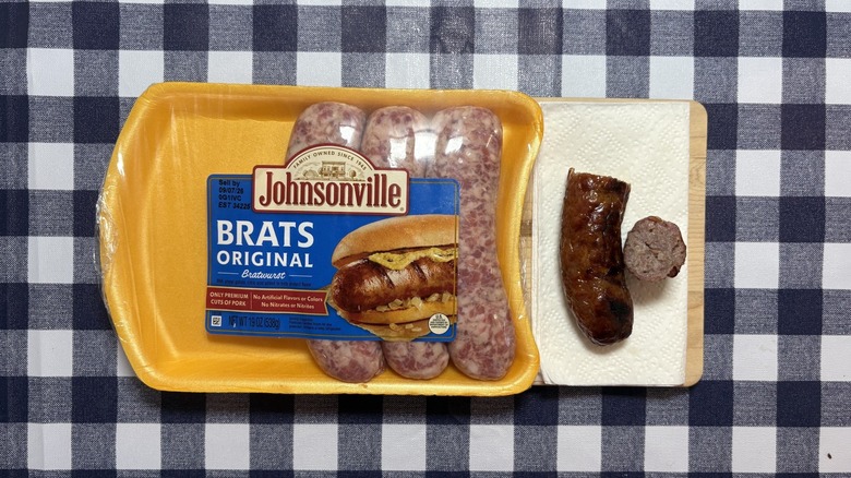 Paquet de brat de Johnsonville à côté de brat cuit coupé en deux sur une nappe à carreaux