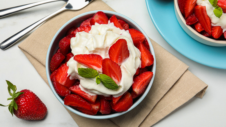 Bol de crème fouettée entouré de fraises.