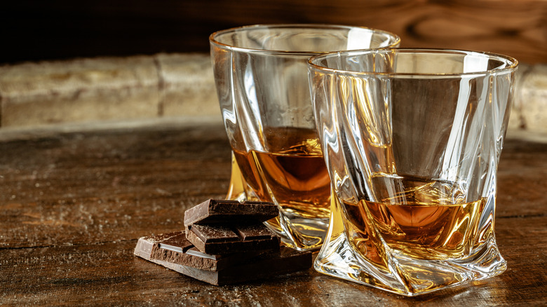 Deux verres de scotch avec quelques morceaux de chocolat noir sur une table