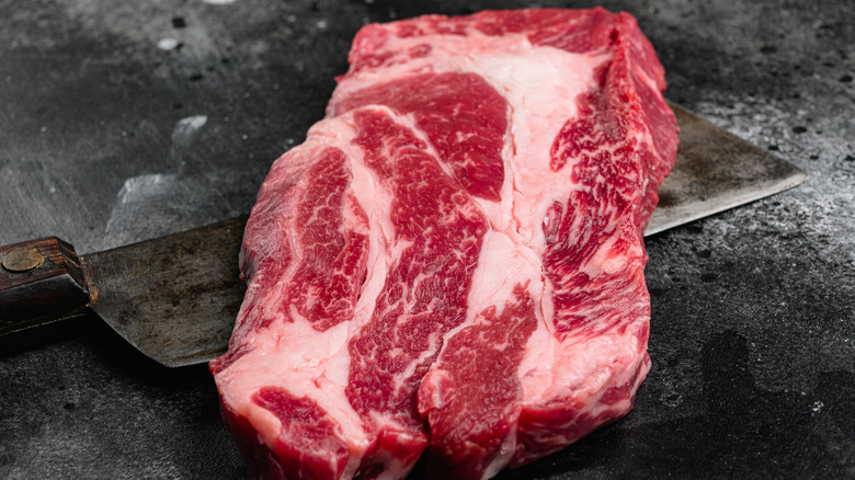Une coupe de steak de paleron sur une table en pierre sombre.