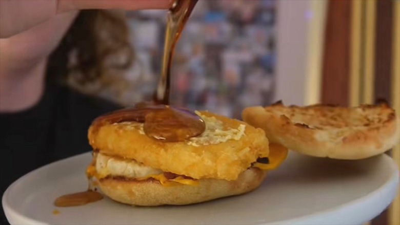 Le sirop d'érable est versé sur un Egg McMuffin garni d'une pomme de terre rissolée McDonald's.