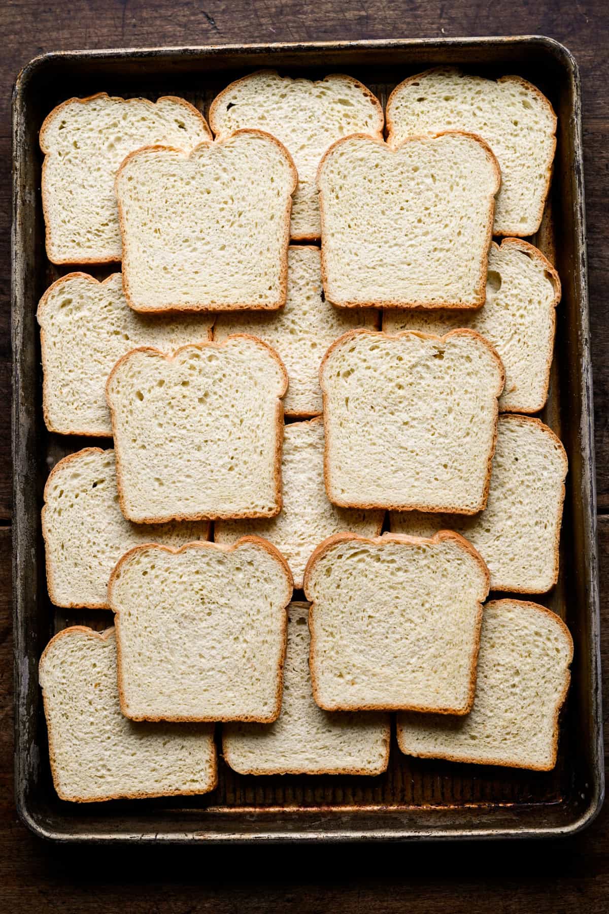 Vue aérienne de tranches de pain de mie blanc surgelé disposées sur une tôle.