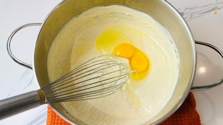 Fouetter les œufs dans la sauce au fromage dans une casserole