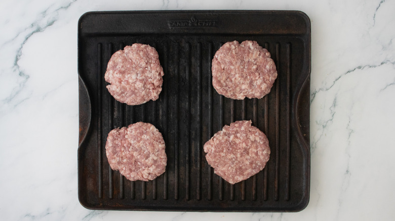 Galettes de porc crues sur une grande poêle à griller