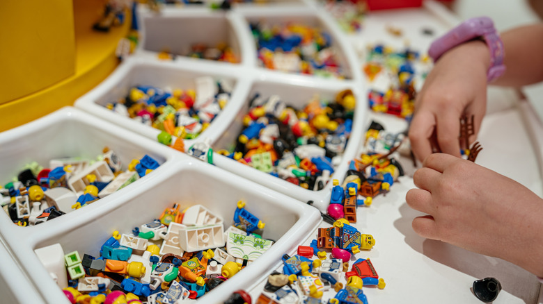 Une paire de mains essayant de construire quelque chose à partir de Legos.