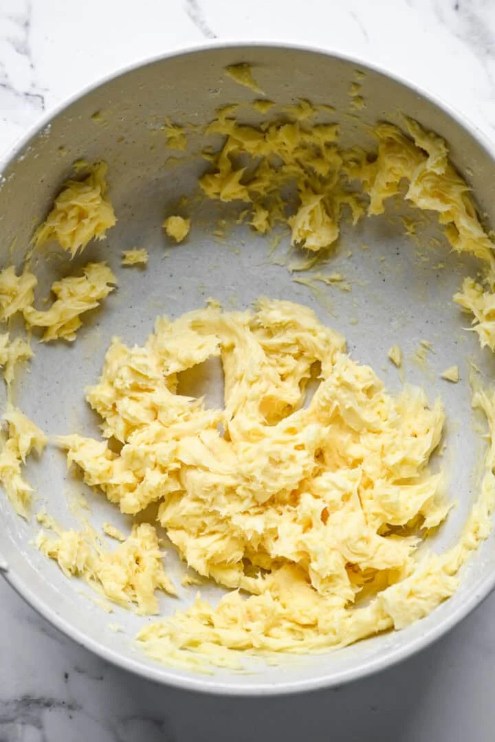 Mélange de beurre crémeux pâle et moelleux dans un grand bol à mélanger moucheté.
