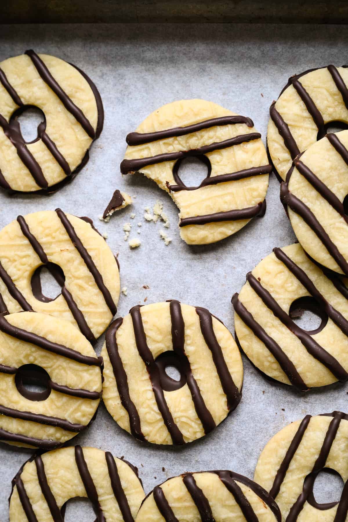 Biscuit rayé au fudge fait maison avec une bouchée retirée et quelques miettes à côté, entouré d'autres biscuits sablés rayés de chocolat sur du papier parchemin.