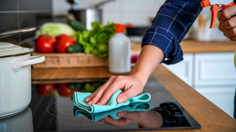 Une personne utilisant un chiffon de nettoyage pour nettoyer une table de cuisson à induction