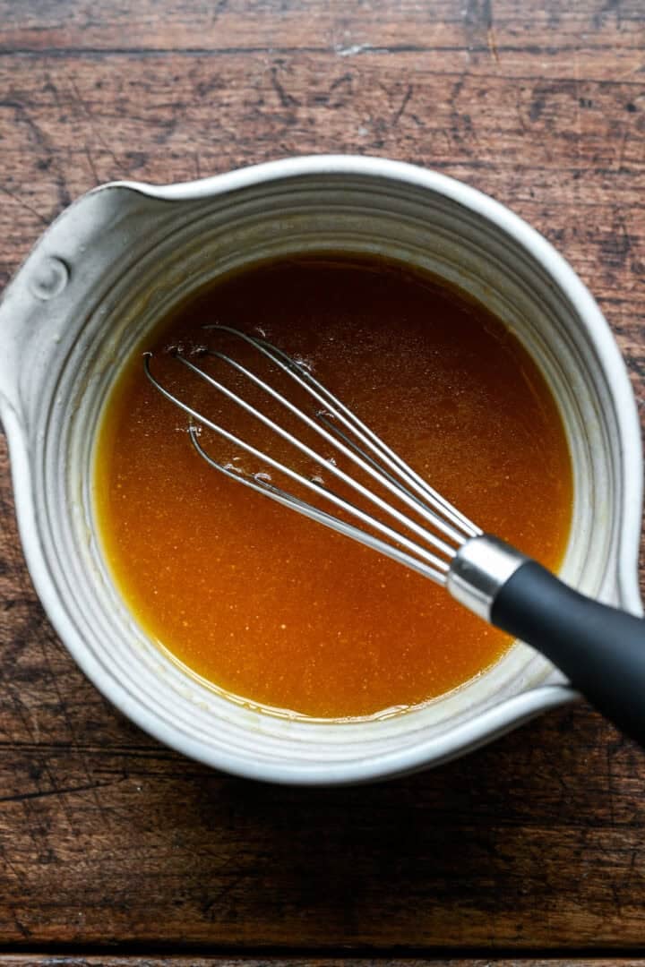 Beurre fondu, sirop d'érable, vanille et bourbon mélangés dans un petit pichet blanc.