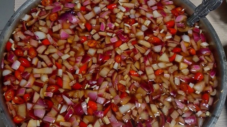 Une grande marmite remplie de vinaigre épicé philippin, où flottent des oignons et du piment