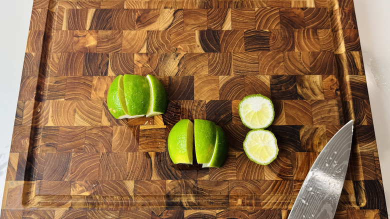 Citron vert coupé en quartiers sur planche de bois