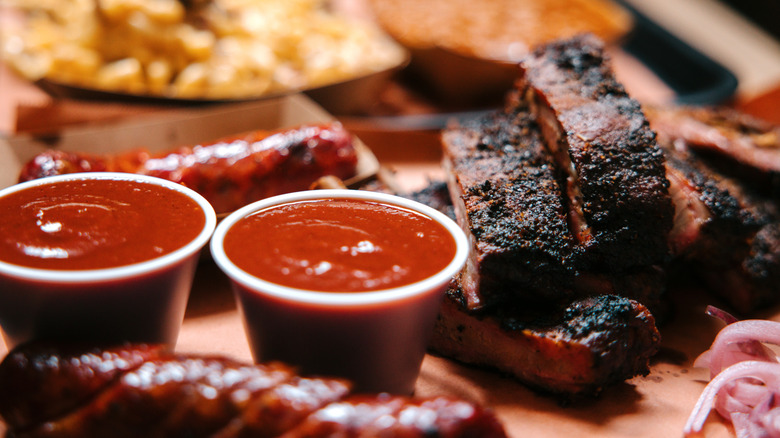 Deux récipients de sauce barbecue à côté des côtes cuites