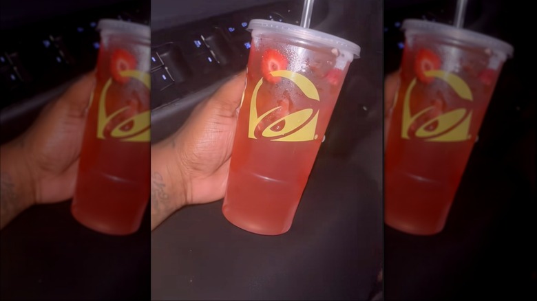 main tenant une tasse de rafraîchisseur d'énergie Taco Bell Strawberry Tropics