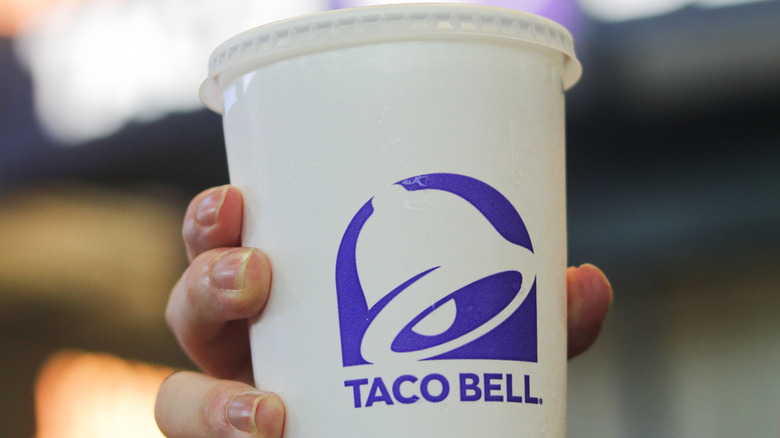 Main tenant une tasse de boisson Taco Bell