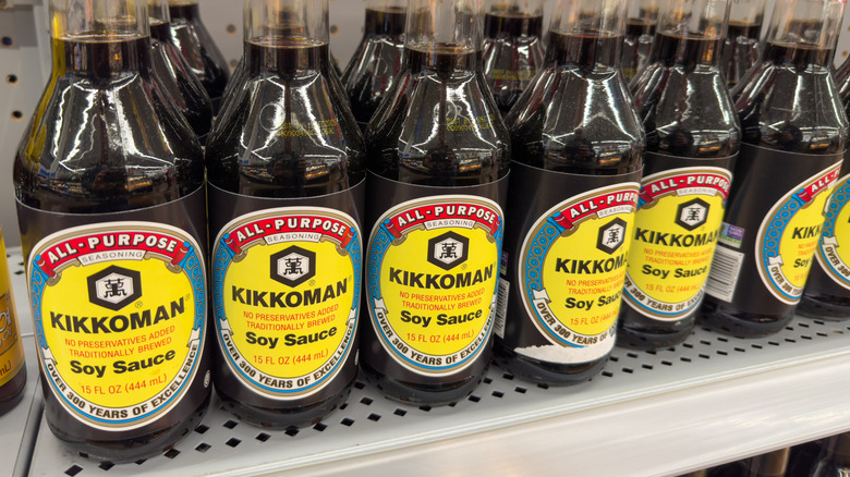 Des bouteilles de sauce soja Kikkoman alignées sur une étagère de magasin.