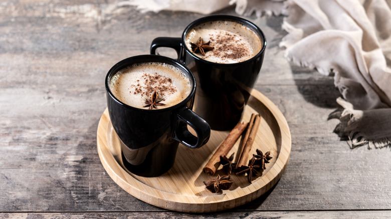 Deux chai lattes sur un plateau en bois avec des épices.