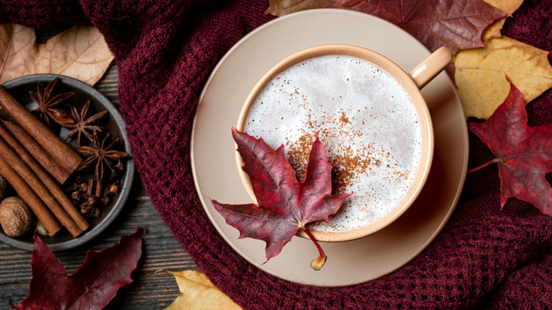 Un latte à l'érable est photographié d'en haut, avec des épices et des feuilles sur le côté.