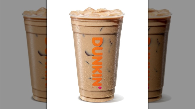 Latte protéiné glacé au chocolat et au caramel dans une tasse en plastique transparent Dunkin sur fond blanc