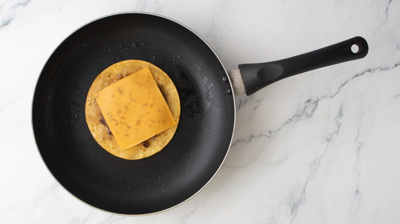 Tranche de fromage fondu sur une tortilla garnie de galettes de burger