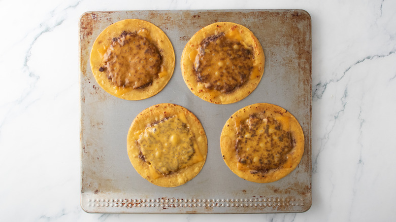Une plaque à biscuits avec quatre hamburgers tacos au fromage