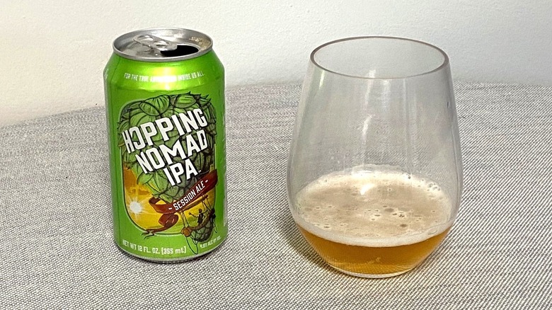 Une canette ouverte de Hopping Nomad IPA à côté d'un verre avec un échantillon