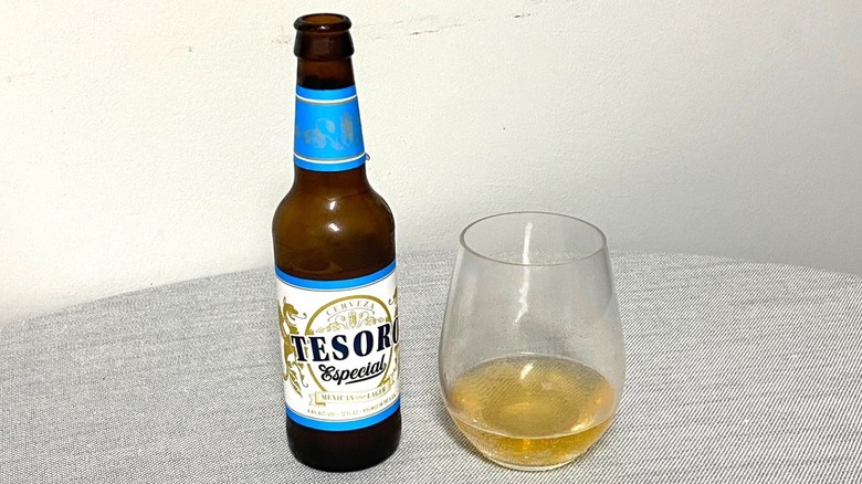 Une bouteille de bière Tesoro Especial sur une table à côté d'un échantillon dans un verre