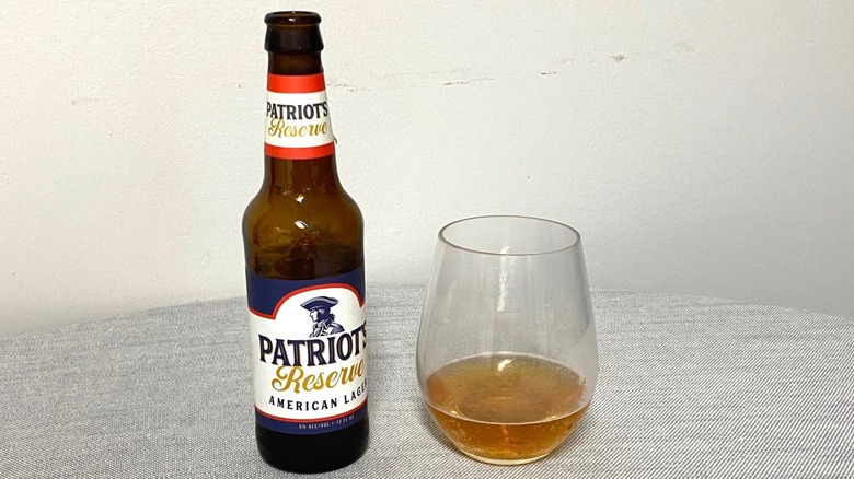 Une bouteille de Patriot's Reserve American Lager sur une table à côté d'un échantillon dans un verre