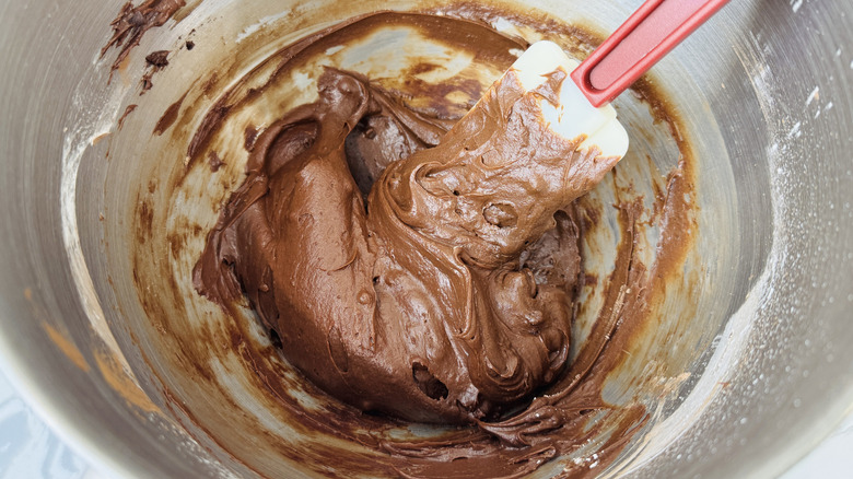 Trempette de pâte à brownie dans le bol du mixeur avec une spatule en caoutchouc