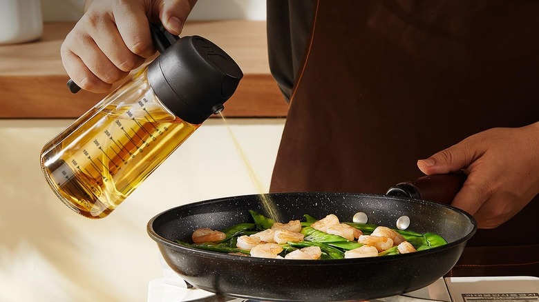 Personne priant l'huile d'olive dans une poêle de crevettes et de légumes