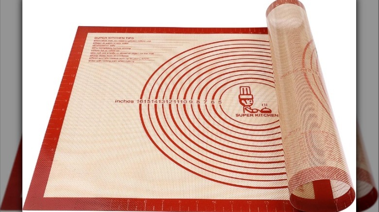 Tapis à pâtisserie en silicone rouge et crème à moitié roulé avec mesures