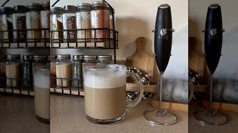 Mousseur à lait Bean Envy à côté d'une tasse de café en verre recouverte de mousse